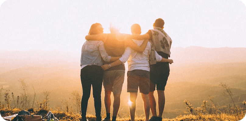 Friends embracing on a hill at sunset